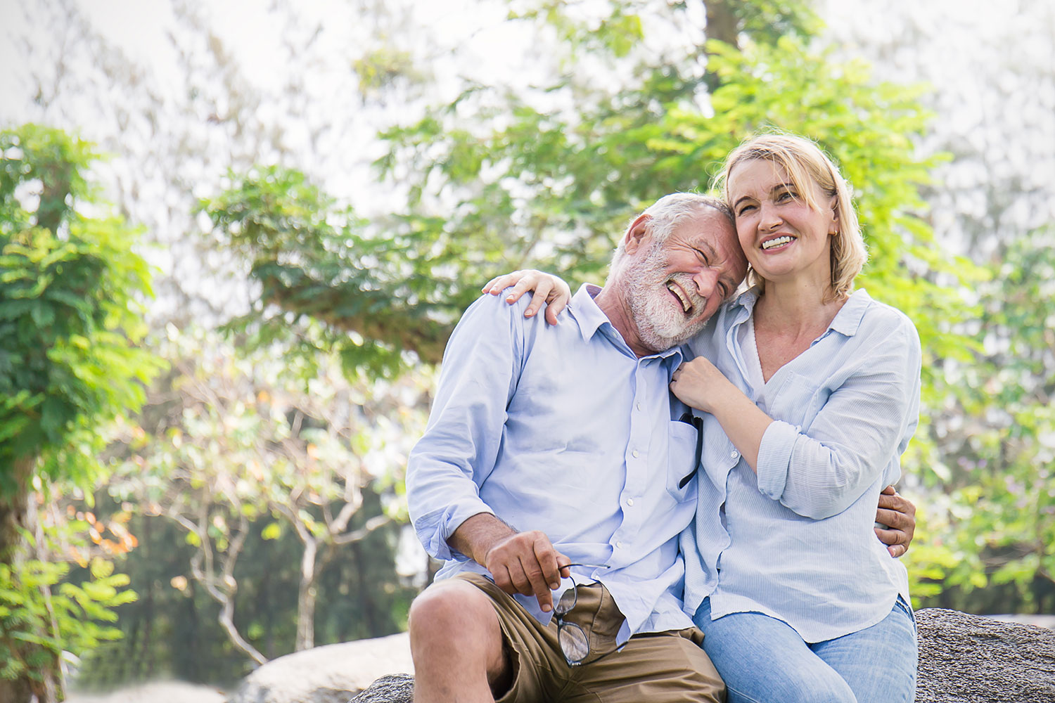 older couple sitting outside and laughing as they hug each other