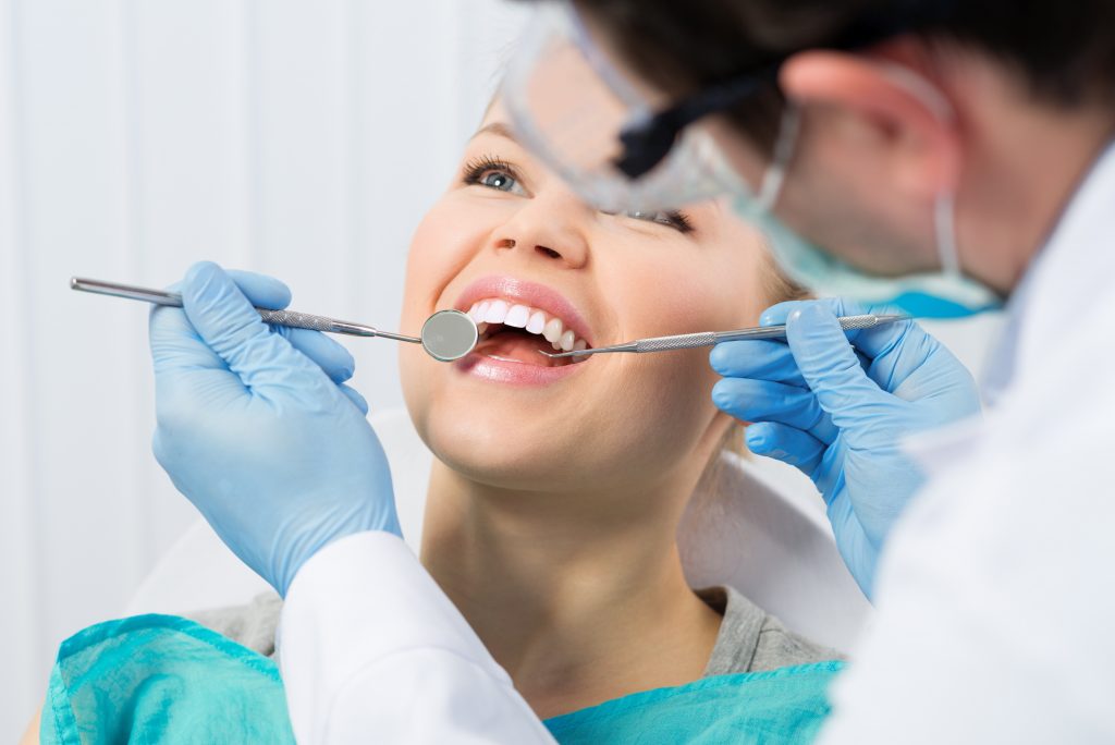 woman's teeth being examined by a dentist