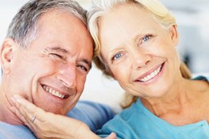 Closeup portrait of a smiling retired couple against bright background